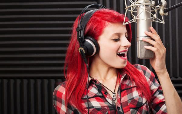 Recording artist singing into a microphone in a sound studio.