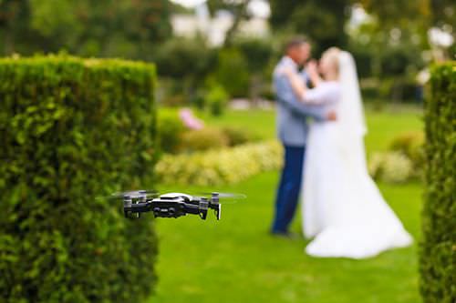 Flying drone taking photo of couple on wedding day.