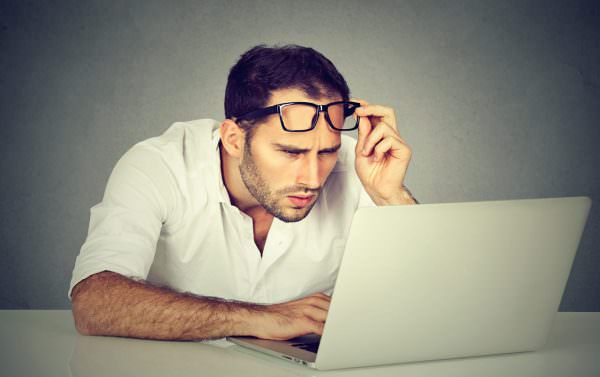 Man staring at computer screen in confusion