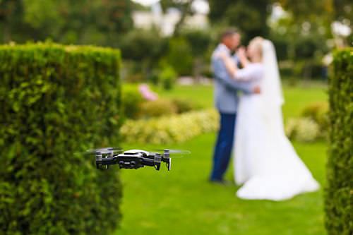 Flying drone taking photo of couple on wedding day.